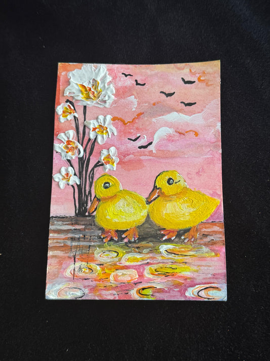 Miniature painting of two yellow ducklings standing near water under a pink sunset sky with flowers and flying birds.