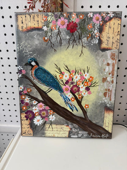 Painting of a blue bird on a branch with flowers and text on a white surface