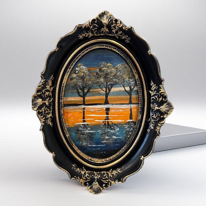 Decorative painting of trees reflected in water with an ornate black and gold frame.