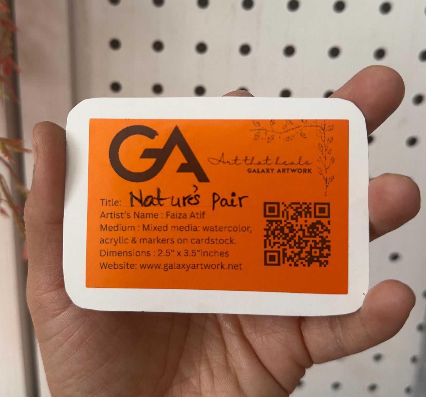 Hand holding a card with Galaxy Artwork branding and information.