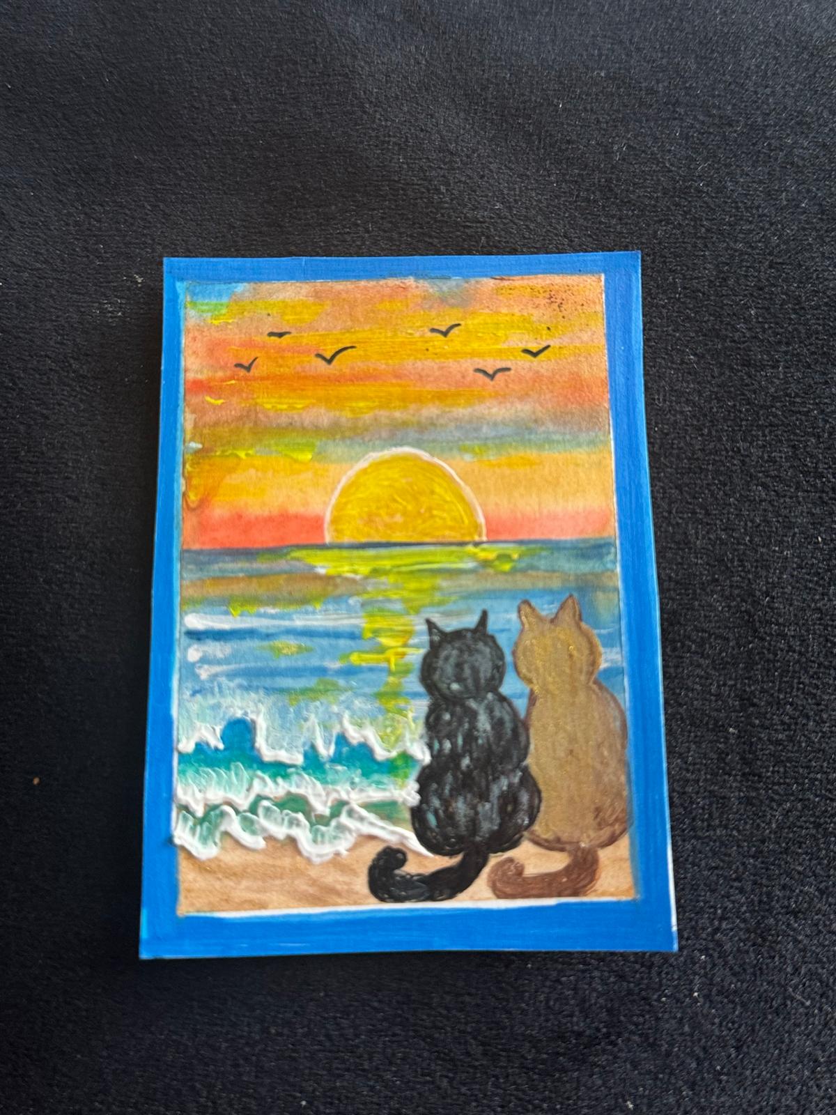“Two cats sitting on the beach watching a colorful sunset over the ocean with waves and birds in the sky.