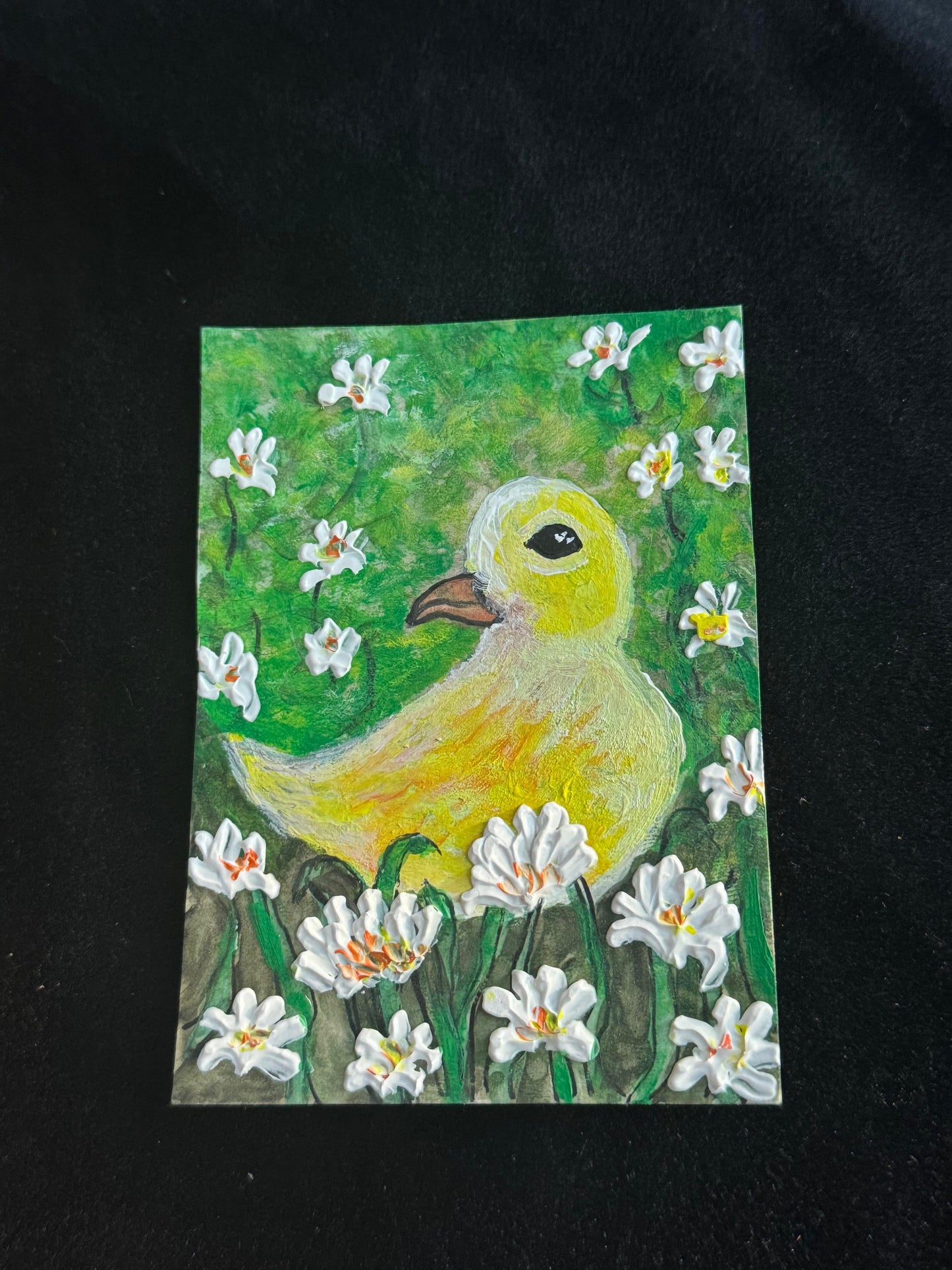 Handmade ACEO artwork of a yellow duck surrounded by white blooming flowers in a green meadow.