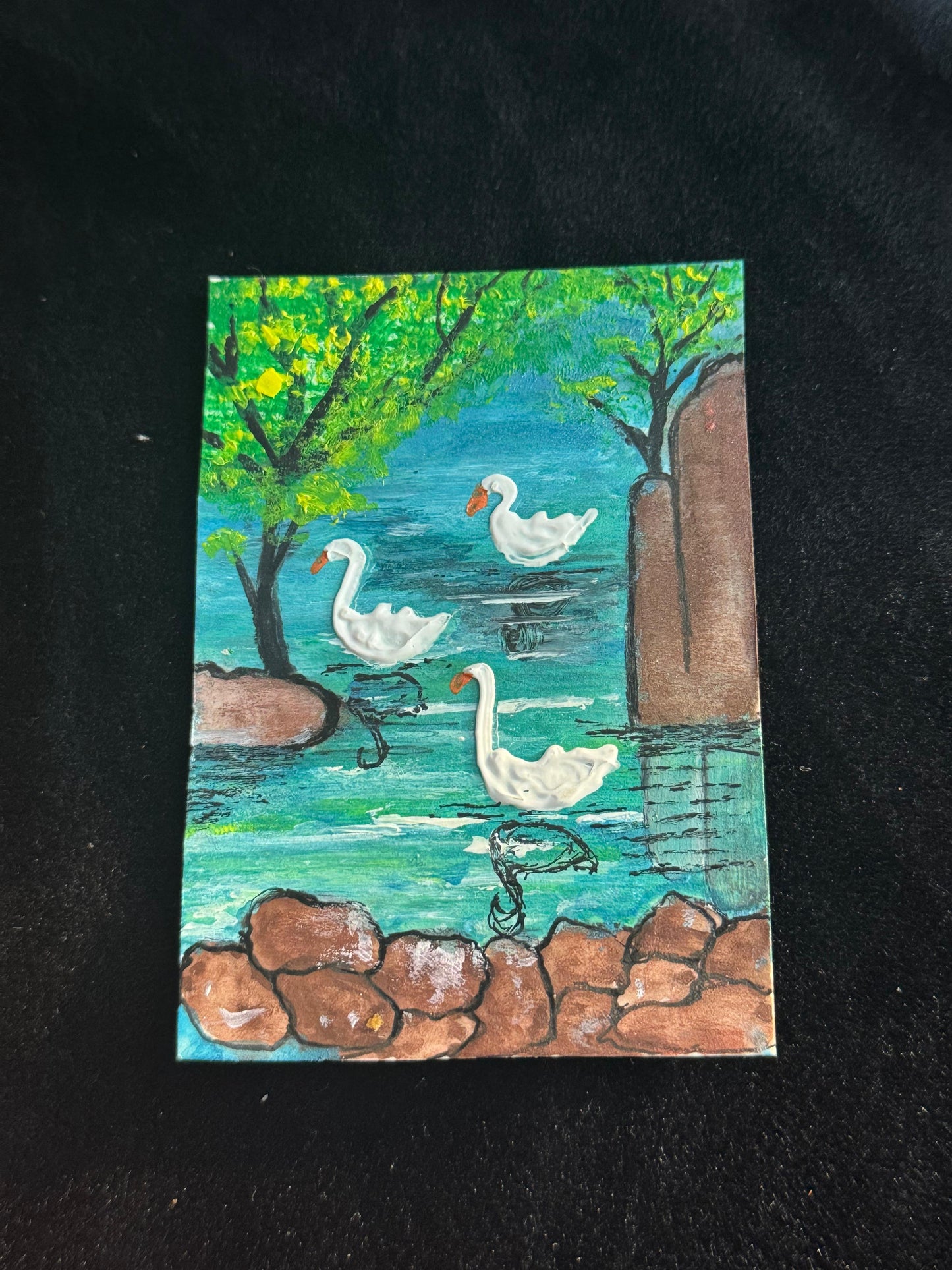 Painting of three swans on a pond with trees and rocks. Mini art card.