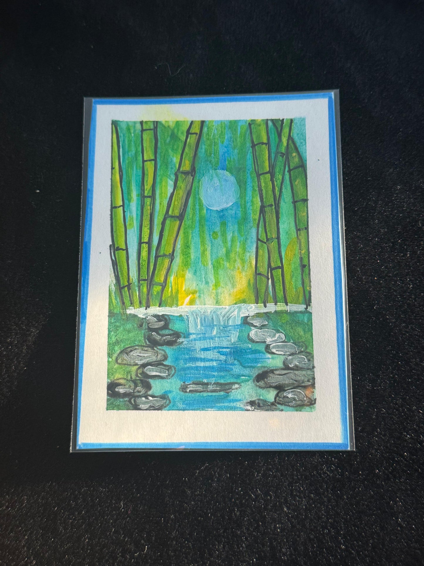 ACEO art card of a moonlit bamboo grove with a flowing waterfall and reflective blue water surrounded by stones.