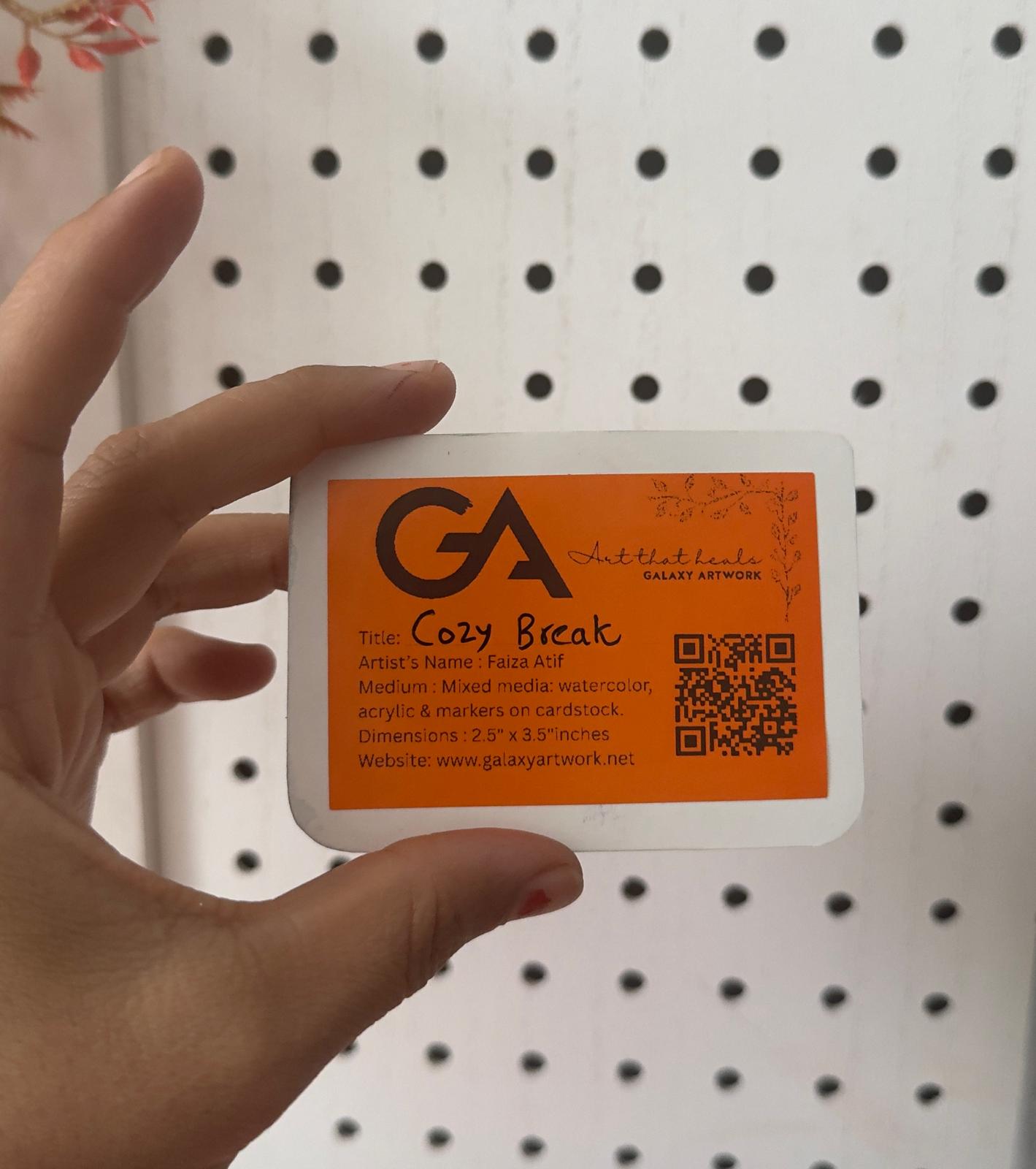 Hand holding a small rectangular card with 'GA' logo and text against a pegboard background