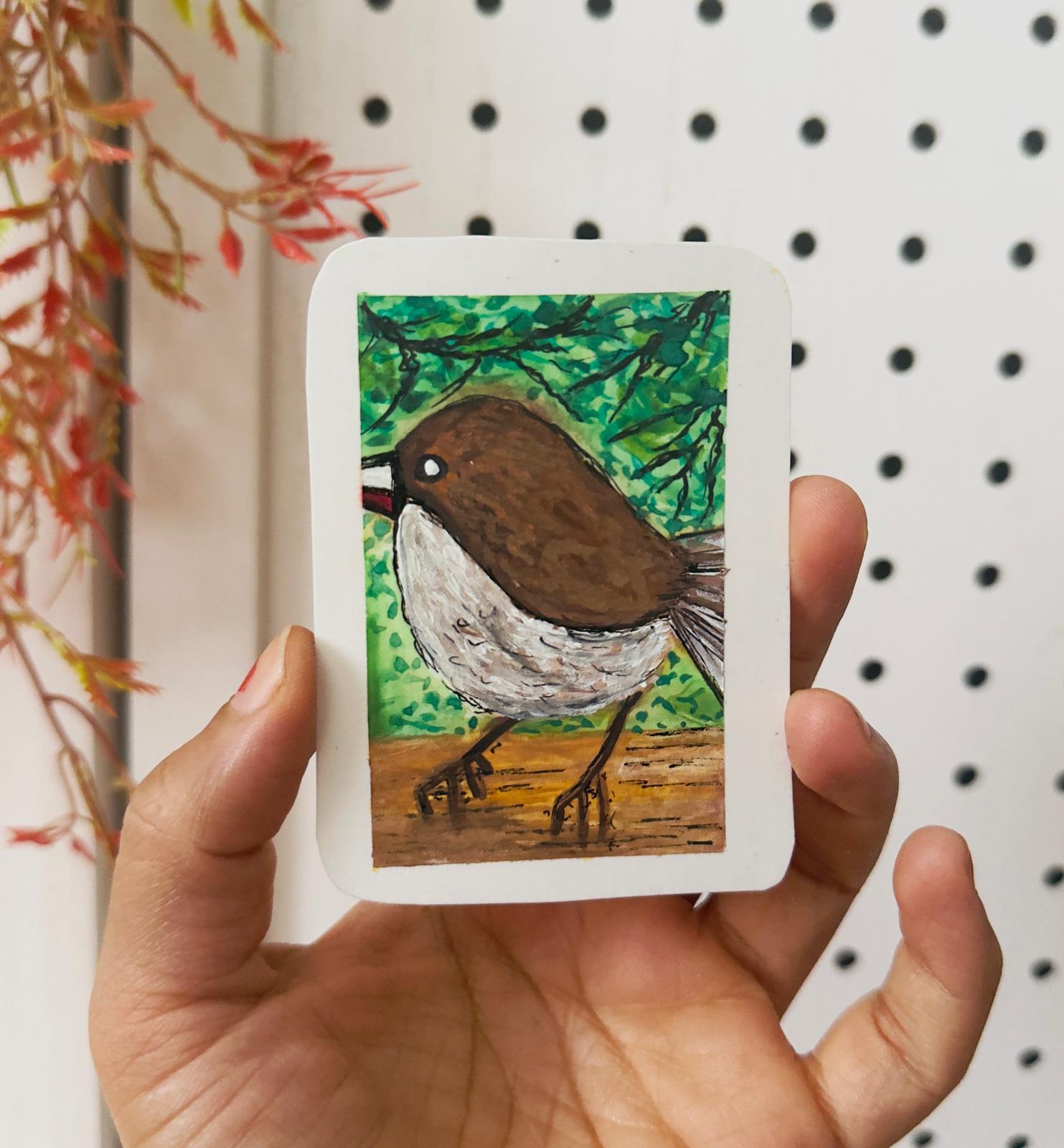Hand-painted ACEO mini art card of a brown sparrow-like bird with white chest standing on the ground, leafy green background.