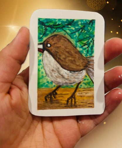 Hand-painted ACEO mini art card of a brown sparrow-like bird with white chest standing on the ground, leafy green background.