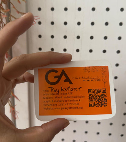Hand holding a business card with 'GA' branding against a pegboard background