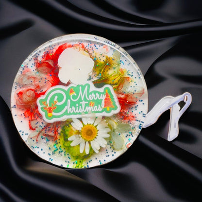 Clear resin Christmas coaster with real daisy flowers, red and green swirls, and Merry Christmas text.