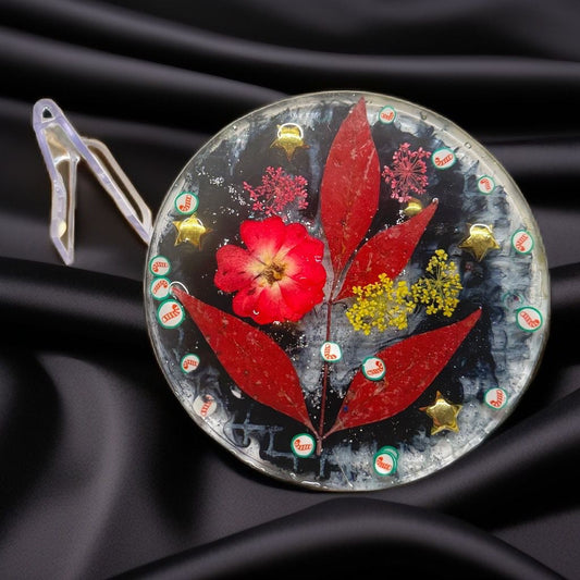 Handmade resin art coaster featuring red leaves, dried flowers, gold stars, and holiday glitter.