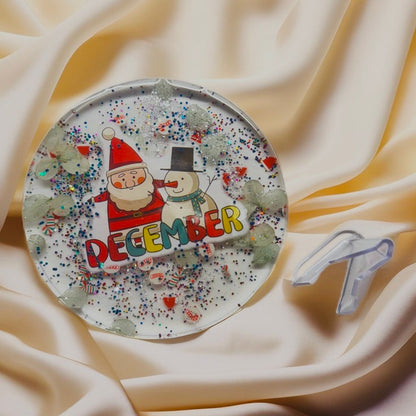 Handmade Merry Christmas resin coaster with red and green wreath-style splash and holiday glitter, round clear resin art.