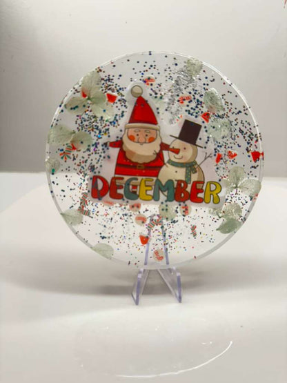 Decorative plate with Santa Claus and a snowman, featuring the word 'December'.