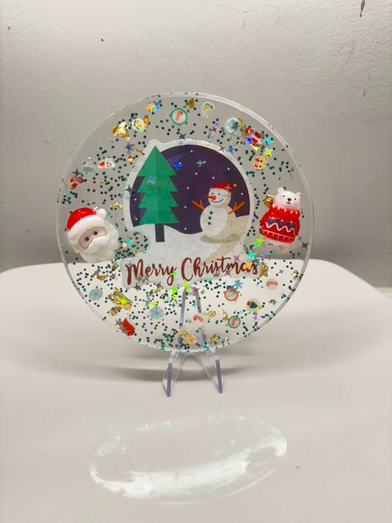 Decorative Christmas plate with festive illustrations on a white stand.