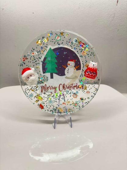 Decorative Christmas plate with festive illustrations on a white stand.