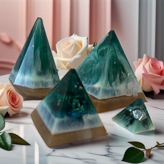 Pyramid-shaped decorative items with green and blue marbled design on a marble surface with roses.