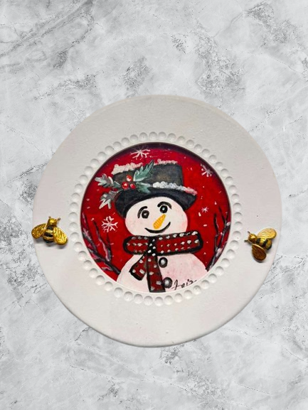 Handmade acrylic mini painting of a snowman in a winter scene on a round white frame with gold bee accents.