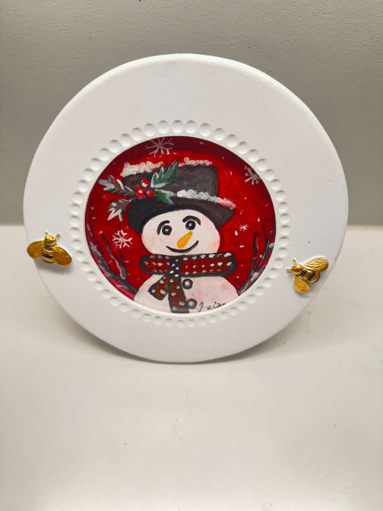 Handmade acrylic mini painting of a snowman in a winter scene on a round white frame with gold bee accents.