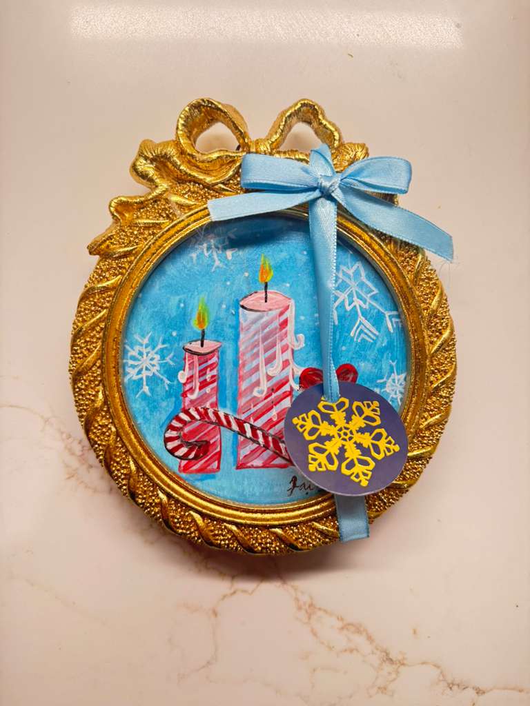 Handmade mini acrylic painting of two striped candles, a wreath, and a candy cane in a round gold frame with a blue ribbon.