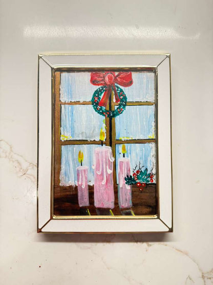 Handmade mini acrylic painting of pink candles glowing on a windowsill with a Christmas wreath and winter background.