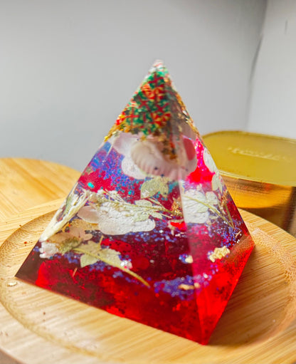Pyramid-shaped resin object with embedded materials on a wooden surface