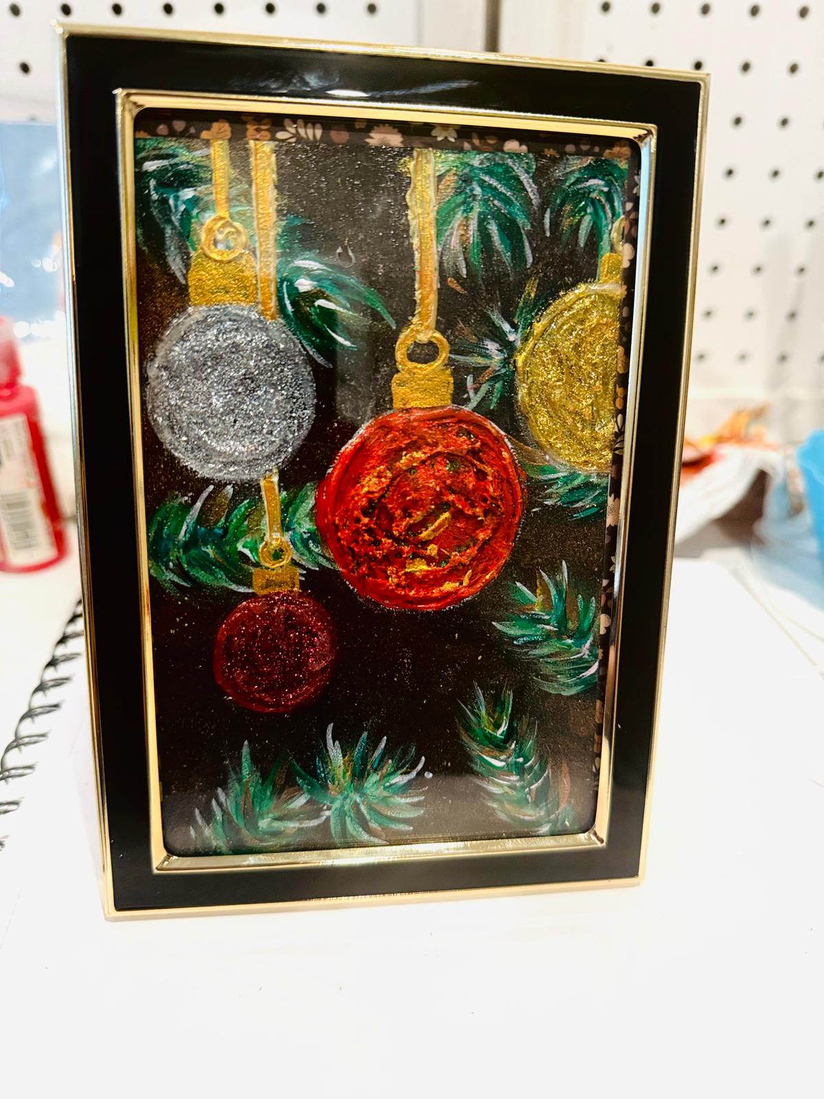 Decorative card with glittery Christmas ornaments and greenery in a gold frame.