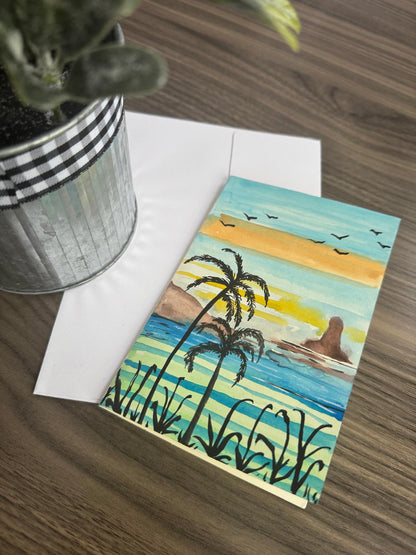 Surrealistic painting of a beach scene with palm trees on a greeting card