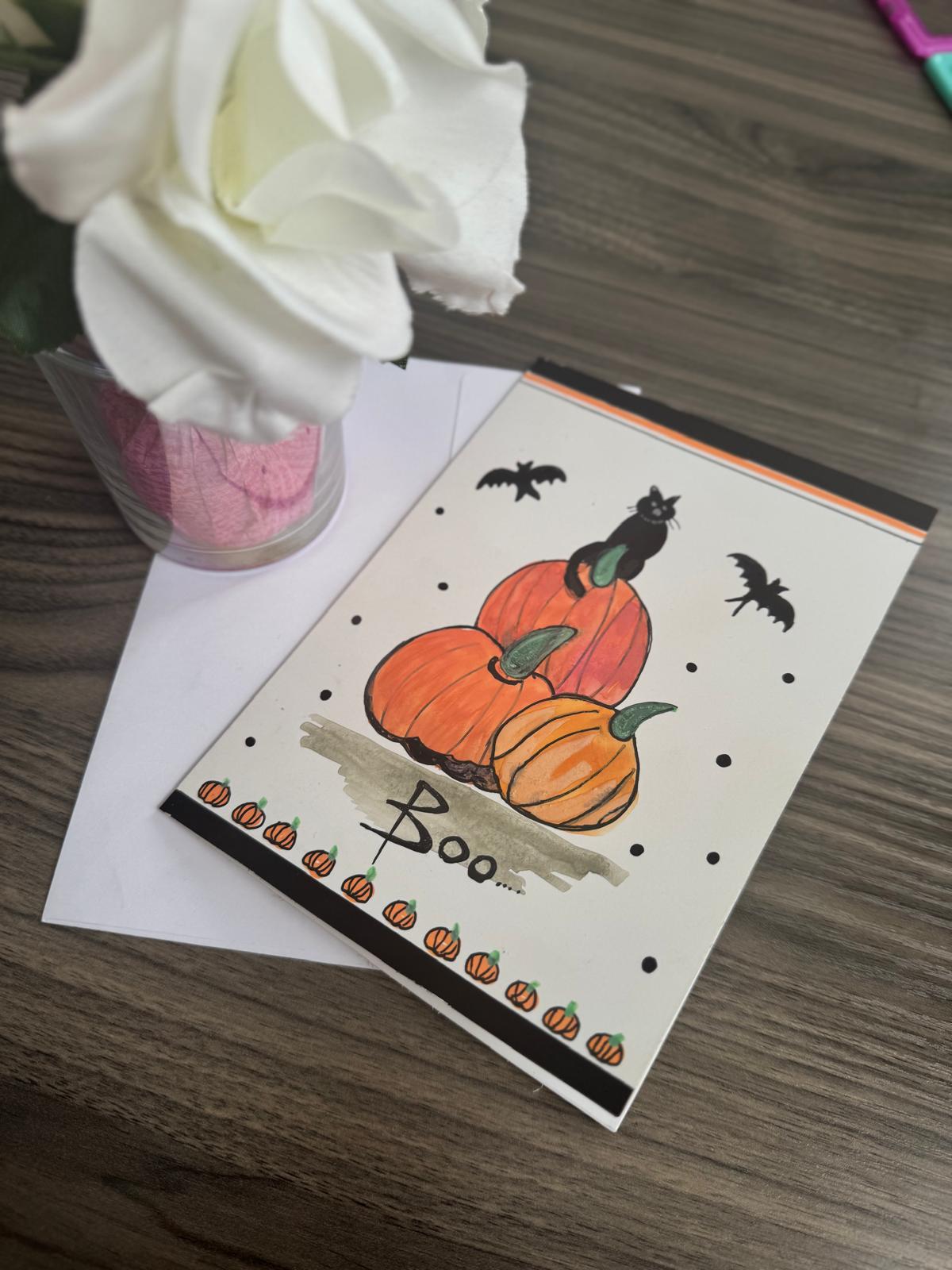 Handmade Halloween card with black cat on pumpkins, bats flying, and Boo text – blank inside with envelope.