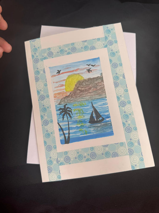 Handmade greeting card with palm trees, sailboat, and sunset over the ocean, blank inside with envelope