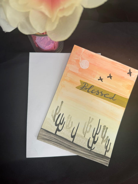 Hand-painted greeting card with desert sunset, cactus silhouettes, and Blessed message – blank inside with envelope.