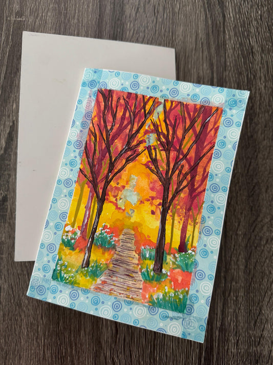 Colorful greeting card with autumn trees and a path .